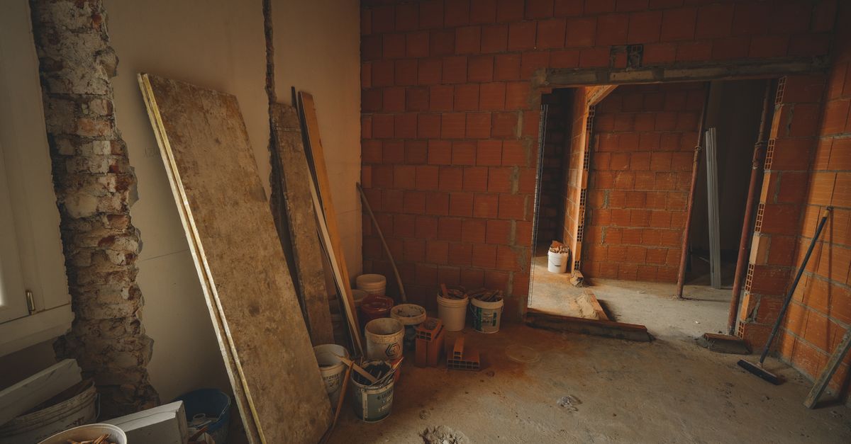 A red brick wall under construction with tools and materials scattered around in a renovation project.