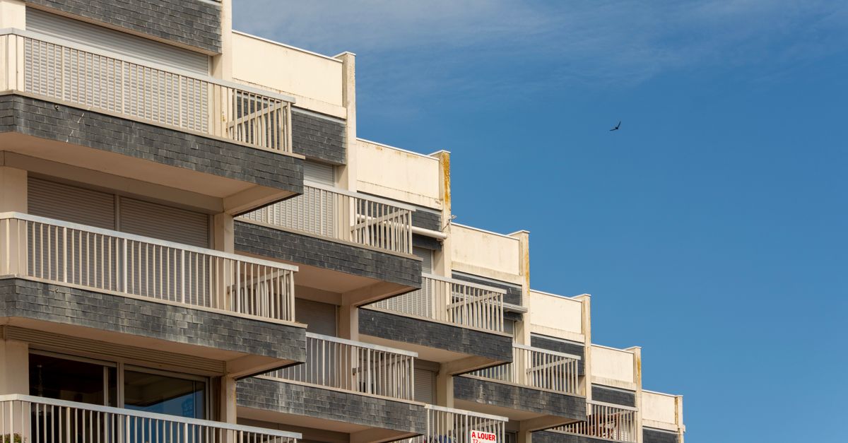 A modern apartment building with distinct balconies against a clear blue sky.